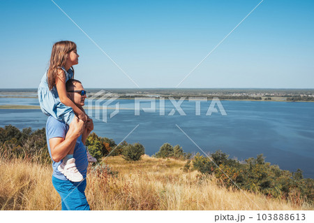 A happy family. Daughter sitting on the shoulders of her father outdoors. 103888613