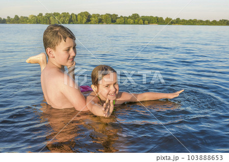 Boy and girl are playing in the water on a sunny day. Happy childhood 103888653