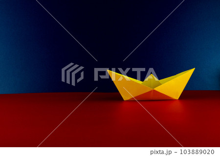 Yellow Origami Boat on a Red Base and Blue Background 103889020