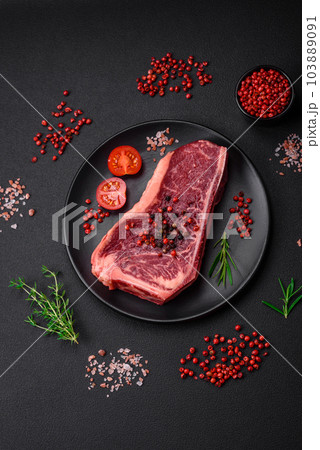 Fresh juicy raw new york beef steak with salt, spices and herbs Fresh juicy raw new york beef steak with salt, spices and herbs 103889091