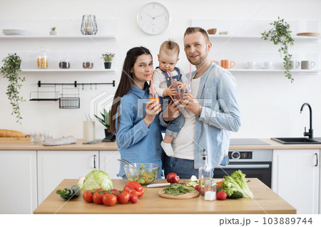 Cheerful family posing on camera with organic juice bottles Cheerful family posing on camera with organic juice bottles 103889744
