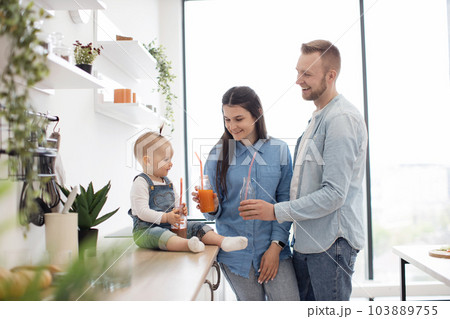 Adorable family of three toasting fresh drinks at home 103889755