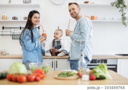 Family in denim attire posing on camera with juice bottles Family in denim attire posing on camera with juice bottles 103889768
