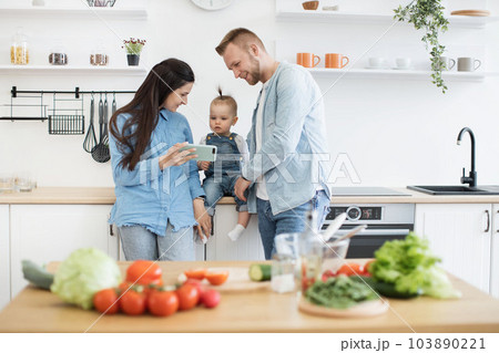 Family searching for recipe of salad on phone in kitchen Family searching for recipe of salad on phone in kitchen 103890221