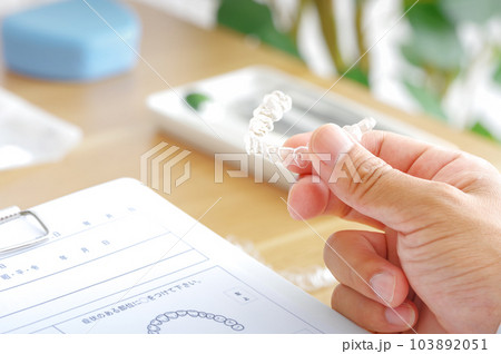 歯科医療で使用するマウスピースの説明をする歯科医 103892051