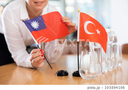 Woman secretary prepares an office for negotiations - she places flags of Taiwan and Turkish table 103894106