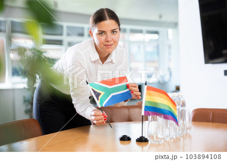 Woman setting South African and LGBT community flags on negotiating table 103894108