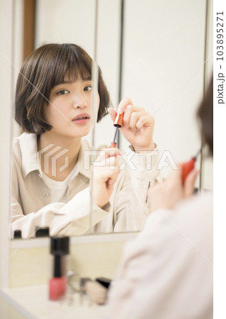 メイクをする女性の鏡越しのポートレート メイクをする女性の鏡越しのポートレート 103895271