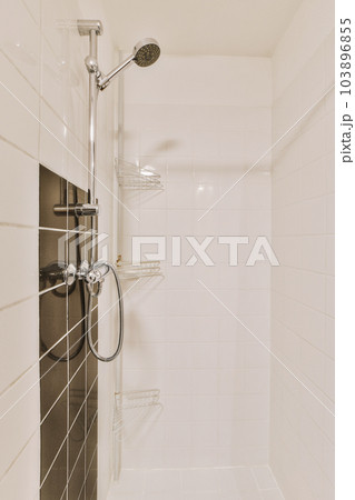 a bathroom with white tiles on the walls and black trim around the tub, shower head and handrails a bathroom with white tiles on the walls and black trim around the tub, shower head and handrails 103896855
