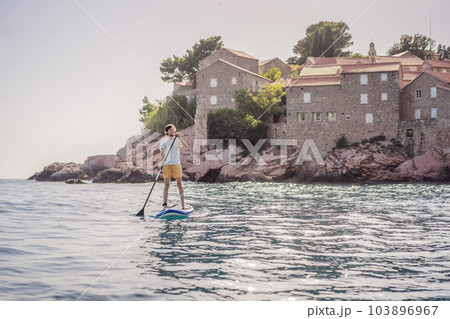 Young men Having Fun Stand Up Paddling in blue water sea near st stefan island in Montenegro. SUP 103896967