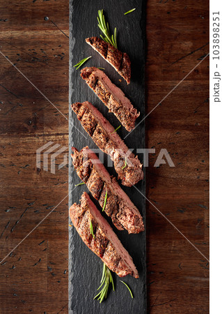 Grilled beef steak on a fork sprinkled with rosemary. 103898251