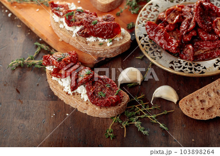 Bruschetta with ricotta, sun-dried tomatoes, and thyme. Bruschetta with ricotta, sun-dried tomatoes, and thyme. 103898264