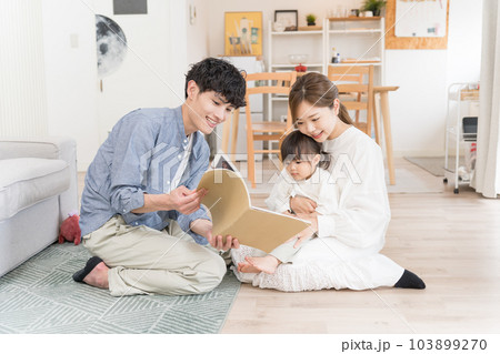 乳幼児に絵本の読み聞かせをする若い夫婦 103899270