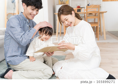 乳幼児に絵本の読み聞かせをする若い夫婦 103899271
