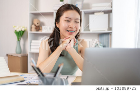 Young Asian female student watching teacher's live performance or video call on laptop in classroom at home, Conversations with teachers and classmates, Online learning, Study at your own home. Young Asian female student watching teacher's live performance or video call on laptop in classroom at home, Conversations with teachers and classmates, Online learning, Study at your own home. 103899725