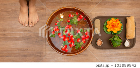 Woman soaks her feet in a bowl with flower petals Woman soaks her feet in a bowl with flower petals 103899942