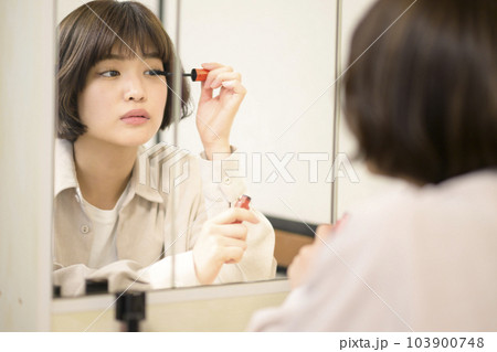 メイクをする女性の鏡越しのポートレート 103900748