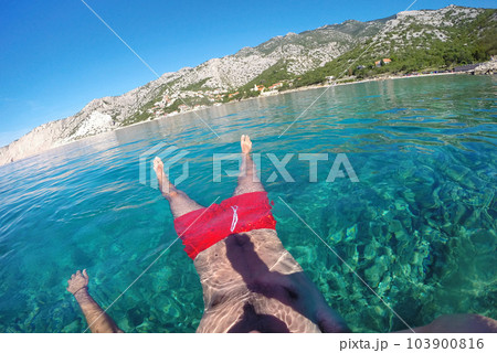 Man floating in sea water Man floating in sea water 103900816