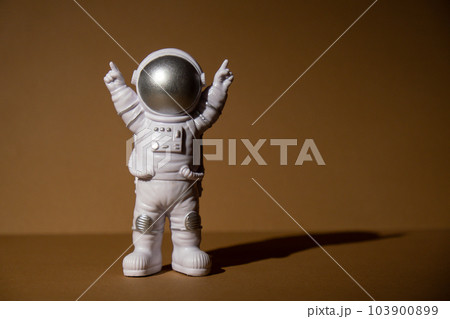 Plastic toy figure astronaut on beige neutral background Copy space. Concept of out of earth travel, private spaceman commercial flights missions and Sustainability 103900899