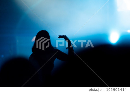 Silhouette of concert crowd in front of bright stage lights 103901414