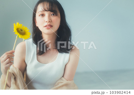 ひまわりの花を持つ若い女性 103902414