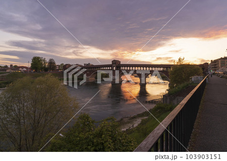 Amazing view of Ponte Coperto (covered bridge) over Ticino river in Pavia at sunset 103903151
