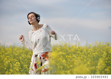 Caucasian girl listening to music with headphone in the outdoors Caucasian girl listening to music with headphone in the outdoors 103903491