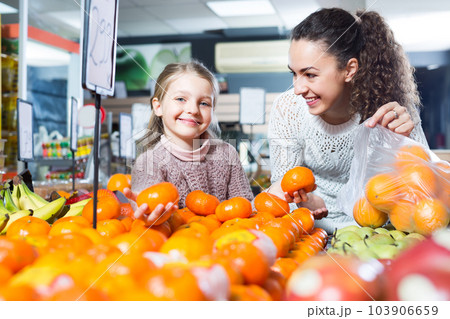 Woman and little girl buying fruits. Woman and little girl buying fruits. 103906659