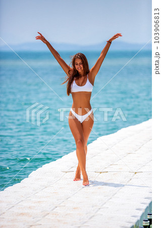 Beautiful girl posing on a pier at the tropical beach Beautiful girl posing on a pier at the tropical beach 103906813