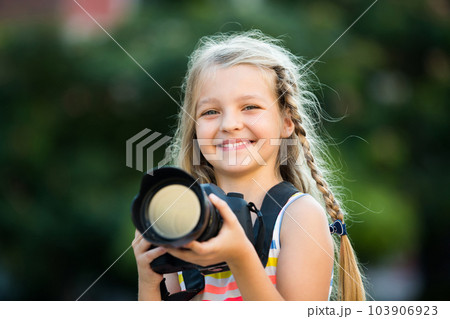 little girl with camera outdoors. 103906923