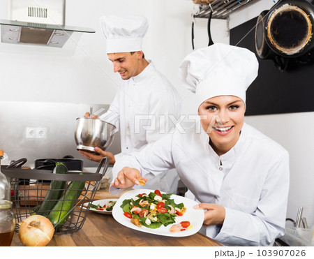 Adult happy female cook holding plate Adult happy female cook holding plate 103907026