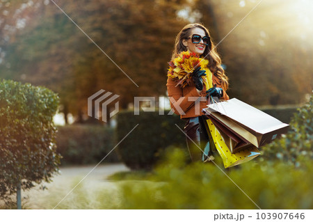 happy modern female in brown trench coat with shopping bags happy modern female in brown trench coat with shopping bags 103907646