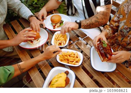 Group of young friends meeting in a cafe eating fresh tasty burgers. Fast food. People. Group of young friends meeting in a cafe eating fresh tasty burgers. Fast food. People. 103908621