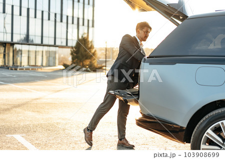 Successful businessman taking luggage from the car trunk 103908699