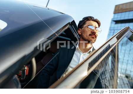 Young handsome businessman in a suit comes out of the luxury car 103908754