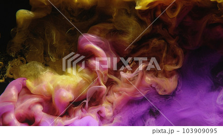 Ink water shot. Color smoke cloud. Fluid mix. Yellow pink purple glowing paint mix splash glitter dust particles on dark black abstract art background. 103909095
