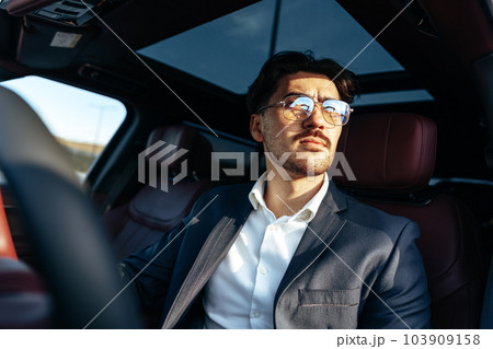 Young businessman in elegant suit driving luxury car 103909158