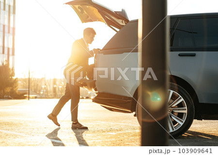 Successful businessman taking luggage from the car trunk 103909641