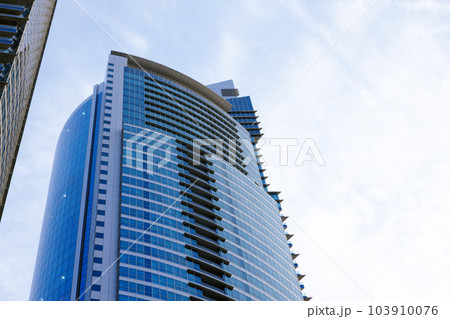Glass skyscraper building with cloudy blue sky background Glass skyscraper building with cloudy blue sky background 103910076