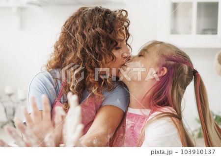 Mother and daughter having fun while cooking dough in kitchen Mother and daughter having fun while cooking dough in kitchen 103910137