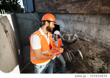 Two young male engineers in uniform and hardhats working at construction site Two young male engineers in uniform and hardhats working at construction site 103910650