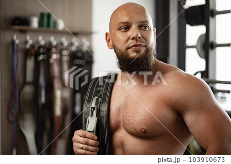 Strong bodybuilder with muscular chest and shoulders in gym Strong bodybuilder with muscular chest and shoulders in gym 103910673