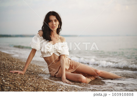 Young relaxed woman sitting all alone on empty beach 103910808