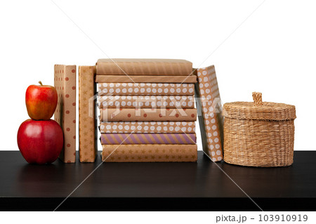 Stack of books and apple on tabletop against white background 103910919