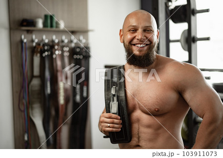 Strong bodybuilder with muscular chest and shoulders in gym Strong bodybuilder with muscular chest and shoulders in gym 103911073