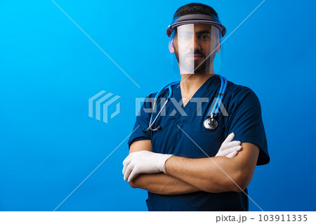 Young arab male doctor standing against blue background 103911335