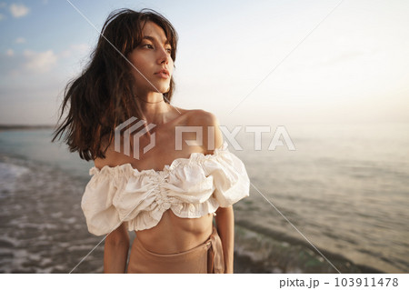 Portrait of young brunette haired woman at the beach at sunset 103911478