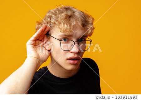 Young handsome man standing over yellow background with hand over ear listening 103911893