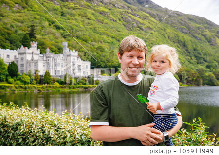 father with little daughter with Kylemore Abbey on background. Man and toddler girl. Family and small children vacations in Ireland father with little daughter with Kylemore Abbey on background. Man and toddler girl. Family and small children vacations in Ireland 103911949