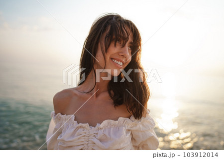 Portrait of young brunette haired woman at the beach at sunset Portrait of young brunette haired woman at the beach at sunset 103912014